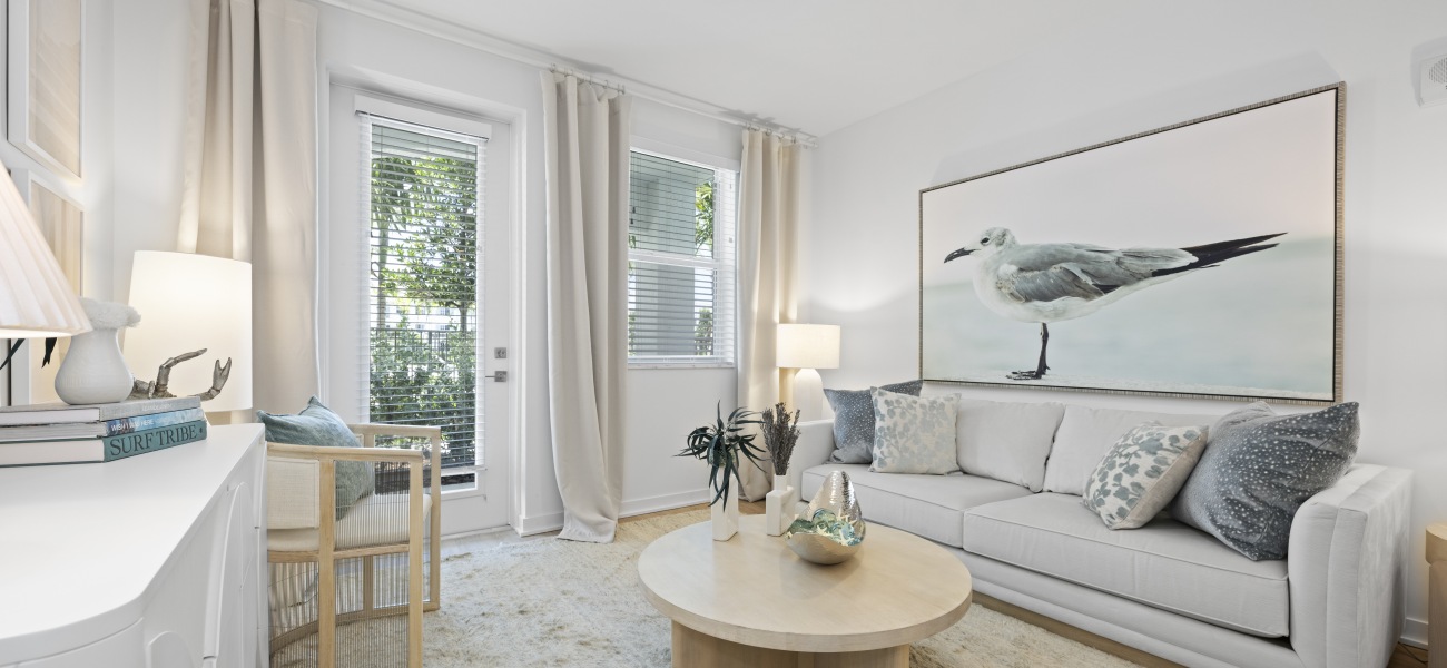 living area sofa coffee table patio door windows curtains credenza wall art of bird