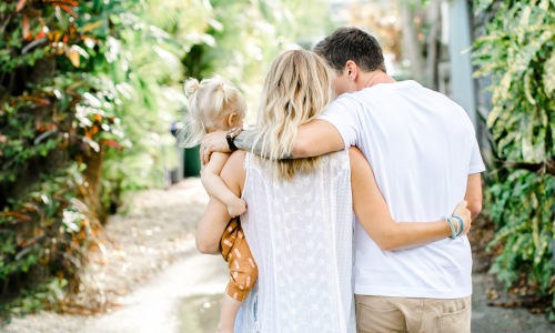 family woman man child white dress paved path lush landscape greenery